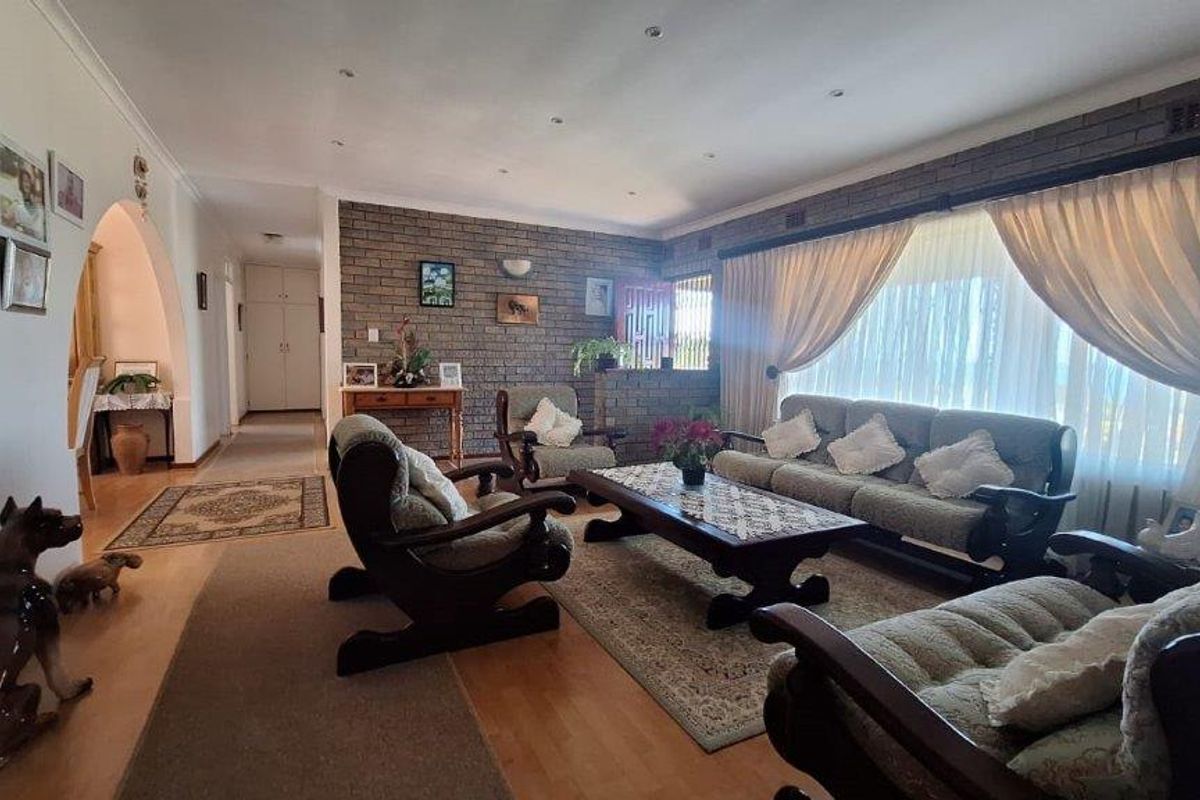 Spacious living room featuring an exposed brick accent wall, laminate flooring, and recessed lighting, creating a warm and inviting atmosphere.