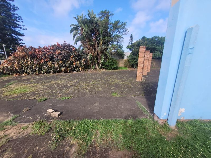 Rear outdoor area featuring concrete paving, brick pillars, and established garden borders, requiring maintenance and landscaping to improve the property's exterior appeal.
