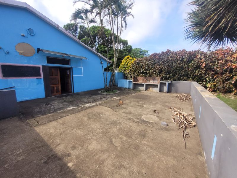Rear exterior area featuring a concrete patio, built-in braai, and boundary walls, requiring maintenance and cosmetic updates to improve the outdoor space.