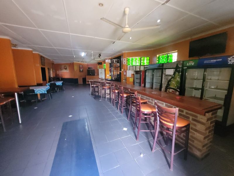 A commercial bar area featuring a built-in brick counter, tiled flooring, and ceiling fans, suitable for hospitality or entertainment use.