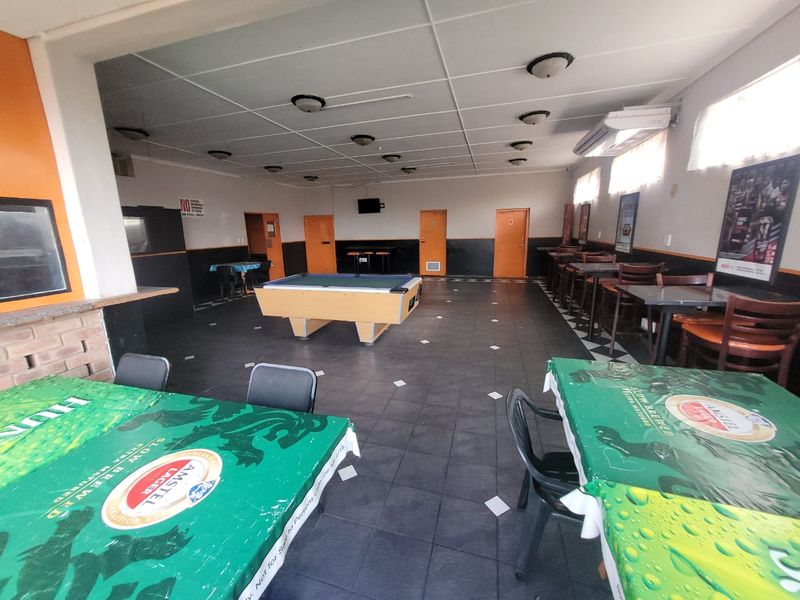 Spacious commercial clubhouse area featuring tiled flooring, wall-mounted air conditioning, and multiple access doors, suitable for social gatherings or entertainment use.