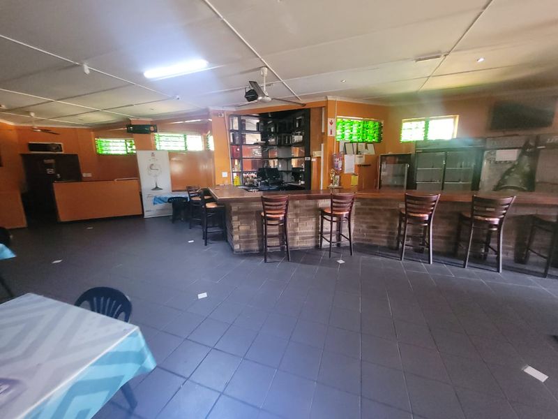 Commercial bar area featuring a brick-faced counter, tiled flooring, and suspended ceiling, offering a functional space for hospitality operations.