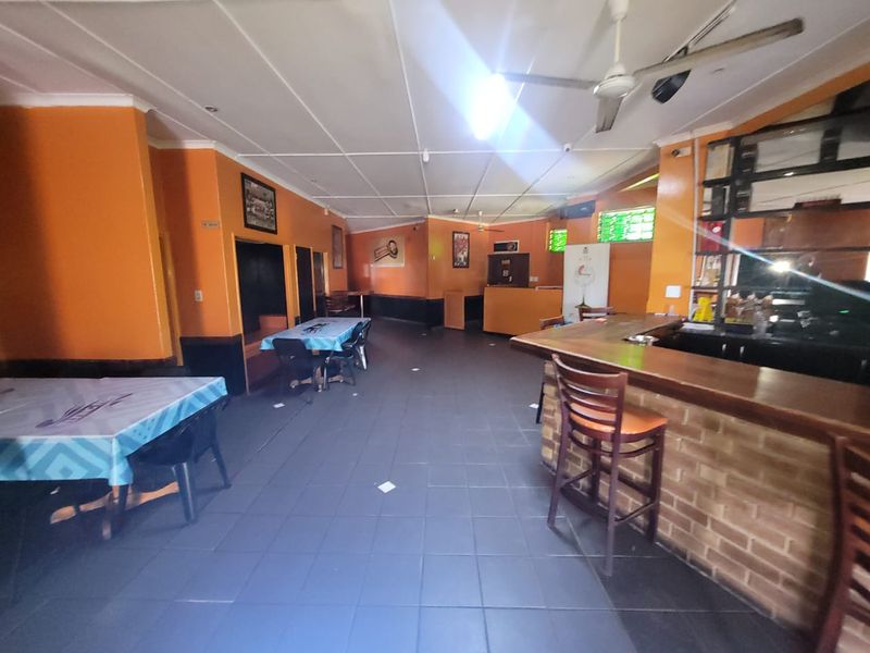 Commercial bar area featuring a built-in brick-base counter, tiled flooring, and ceiling fans, offering a functional space for hospitality operations.