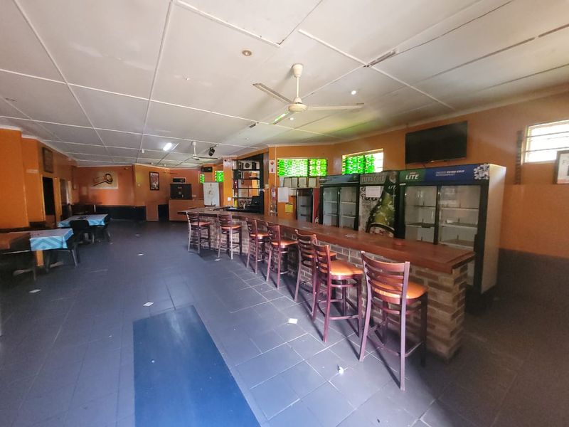 A commercial bar area featuring a built-in brick-base counter, tiled flooring, and ceiling fans, offering a functional space for hospitality operations.