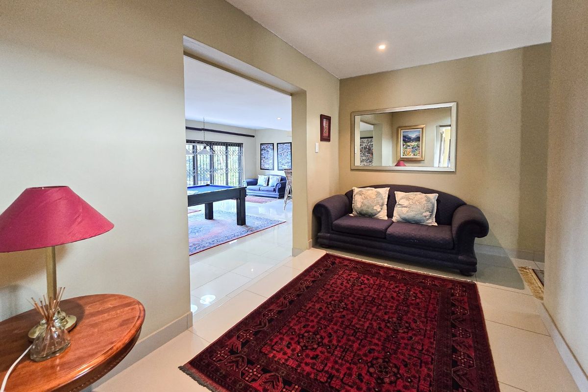 A well-maintained living area featuring neutral wall tones, polished tiled flooring, and recessed lighting, leading into an adjacent recreational space.
