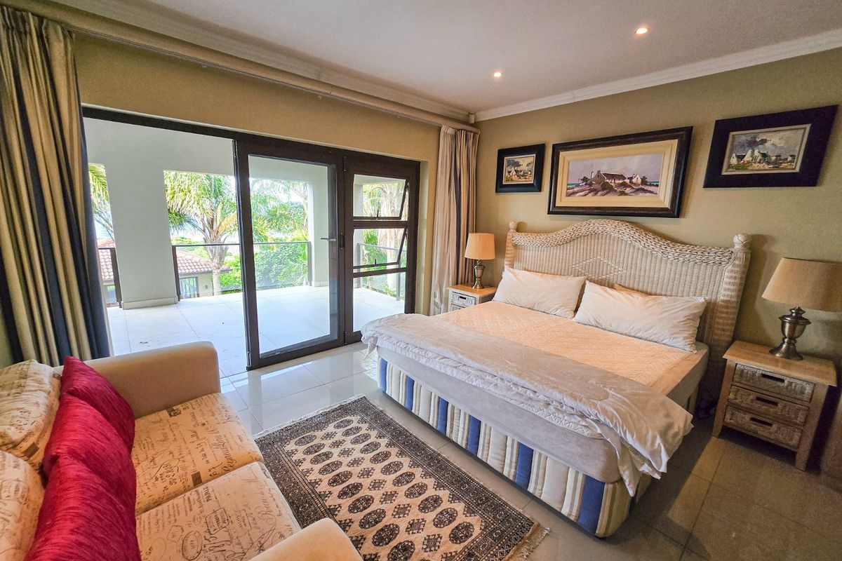 Spacious bedroom featuring tiled flooring, recessed lighting, and large sliding glass doors providing direct access to a private balcony.
