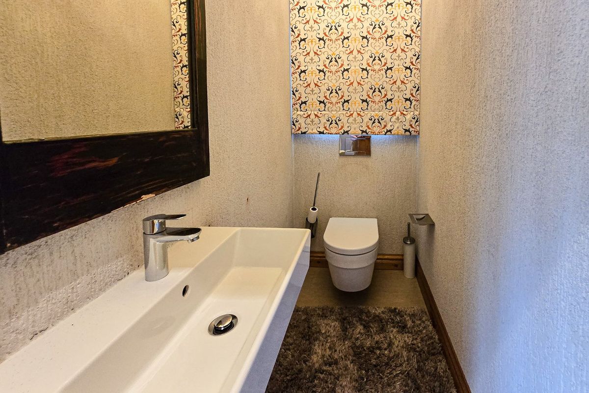 A compact guest cloakroom featuring a wall-mounted basin with chrome mixer tap and a modern wall-hung toilet.