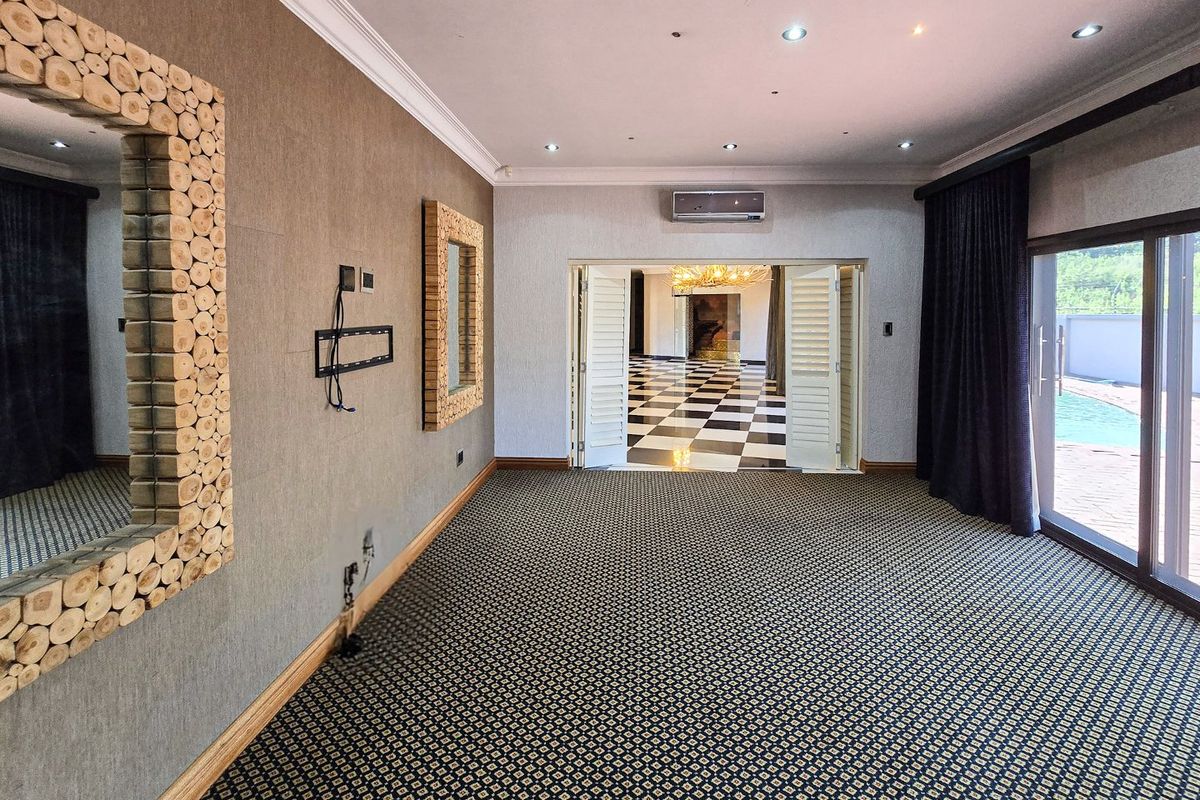 Spacious living area featuring patterned carpeting, recessed ceiling lighting, a wall-mounted air conditioning unit, and sliding glass doors leading to an outdoor pool area.