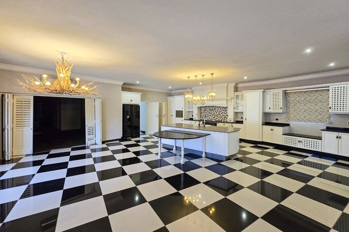 Spacious kitchen featuring a large central island, custom cabinetry, integrated appliances, and a distinctive black and white checkered tiled floor.