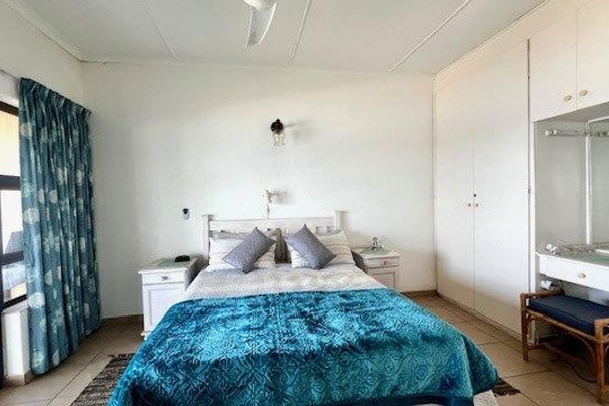 A bedroom featuring built-in cupboards, an integrated vanity area, a ceiling fan, and a sliding glass door providing access to an outdoor space.