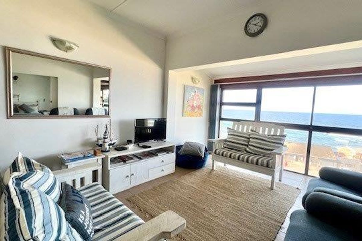 A bright living room featuring large sliding glass doors that offer expansive ocean views and provide ample natural light.