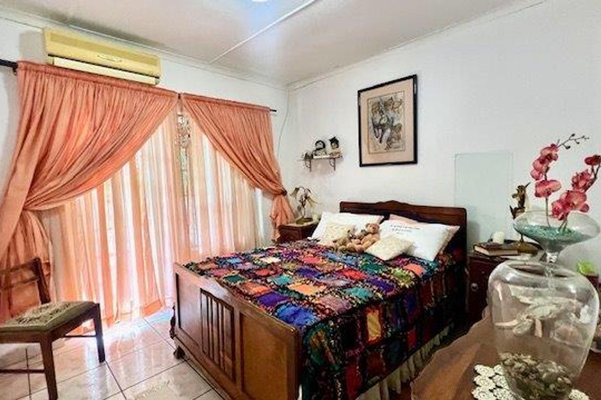 A bedroom featuring tiled flooring, a split-system air conditioner, and a sliding glass door providing access to the exterior.