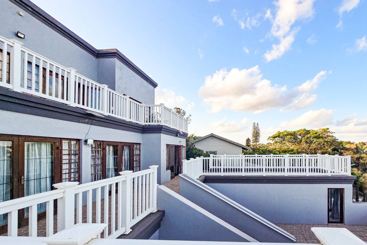 Spacious multi-level rear terrace and balcony area featuring white railings and paved flooring, offering an elevated outdoor living space.