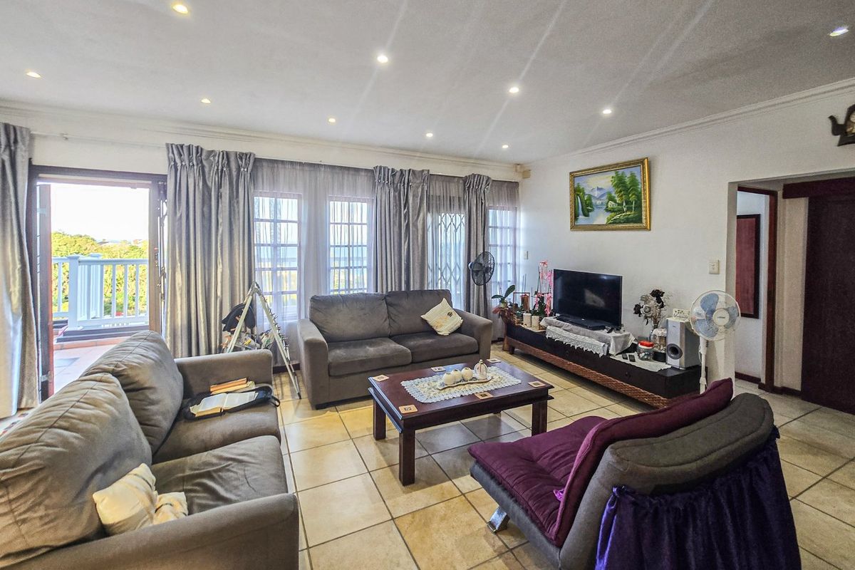Spacious living room featuring tiled flooring, recessed lighting, and large sliding doors providing access to an outdoor balcony area.