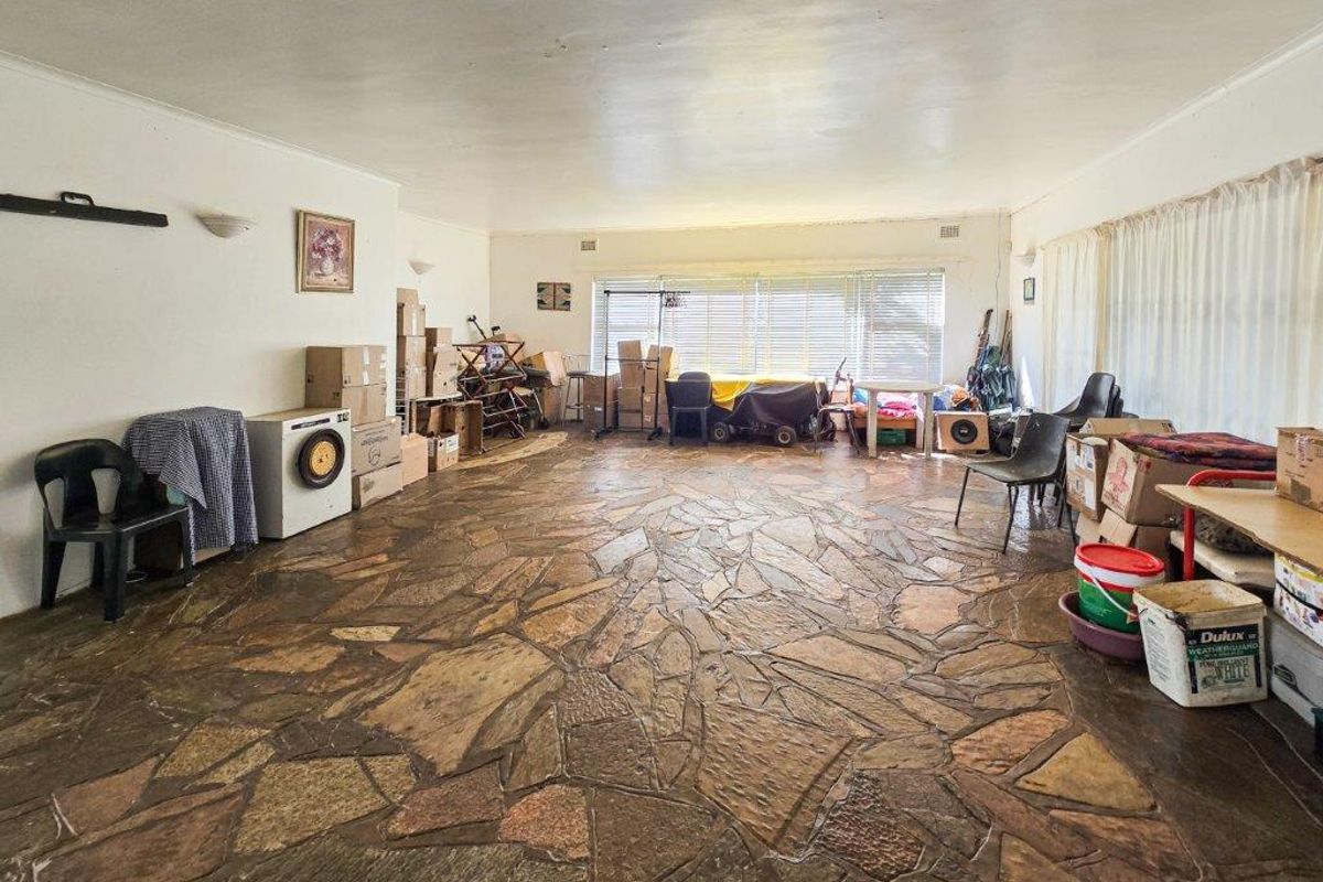 Spacious living area featuring unique flagstone flooring and large windows, offering a blank canvas for renovation and interior design updates.
