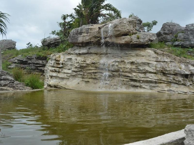 A naturalistic rock pool feature with an integrated waterfall, set within a landscaped farm garden environment.