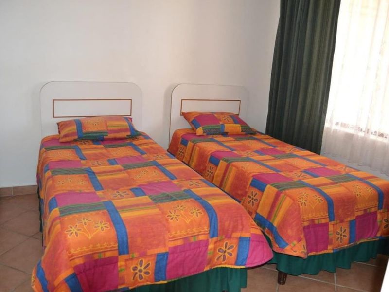 A functional bedroom featuring tiled flooring and window treatments, providing a simple and practical living space.