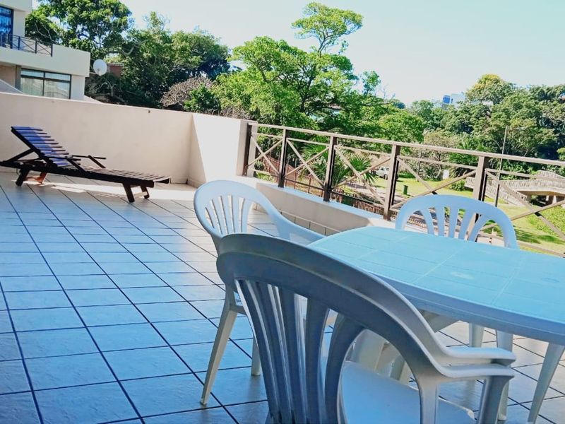 Spacious balcony featuring tiled flooring and a metal balustrade, offering an open outdoor area with views of the surrounding greenery.