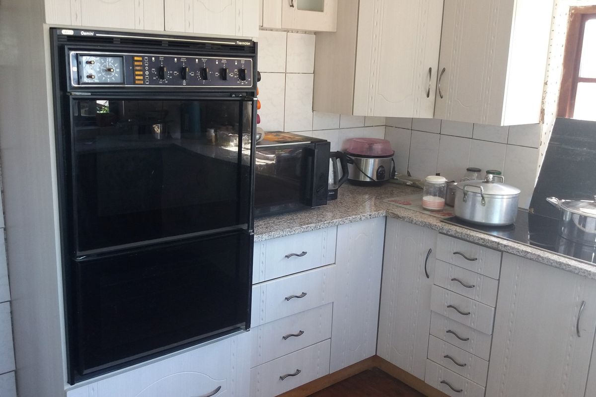 A functional kitchen featuring white cabinetry, granite countertops, a built-in double oven, and an electric cooktop with tiled backsplash.