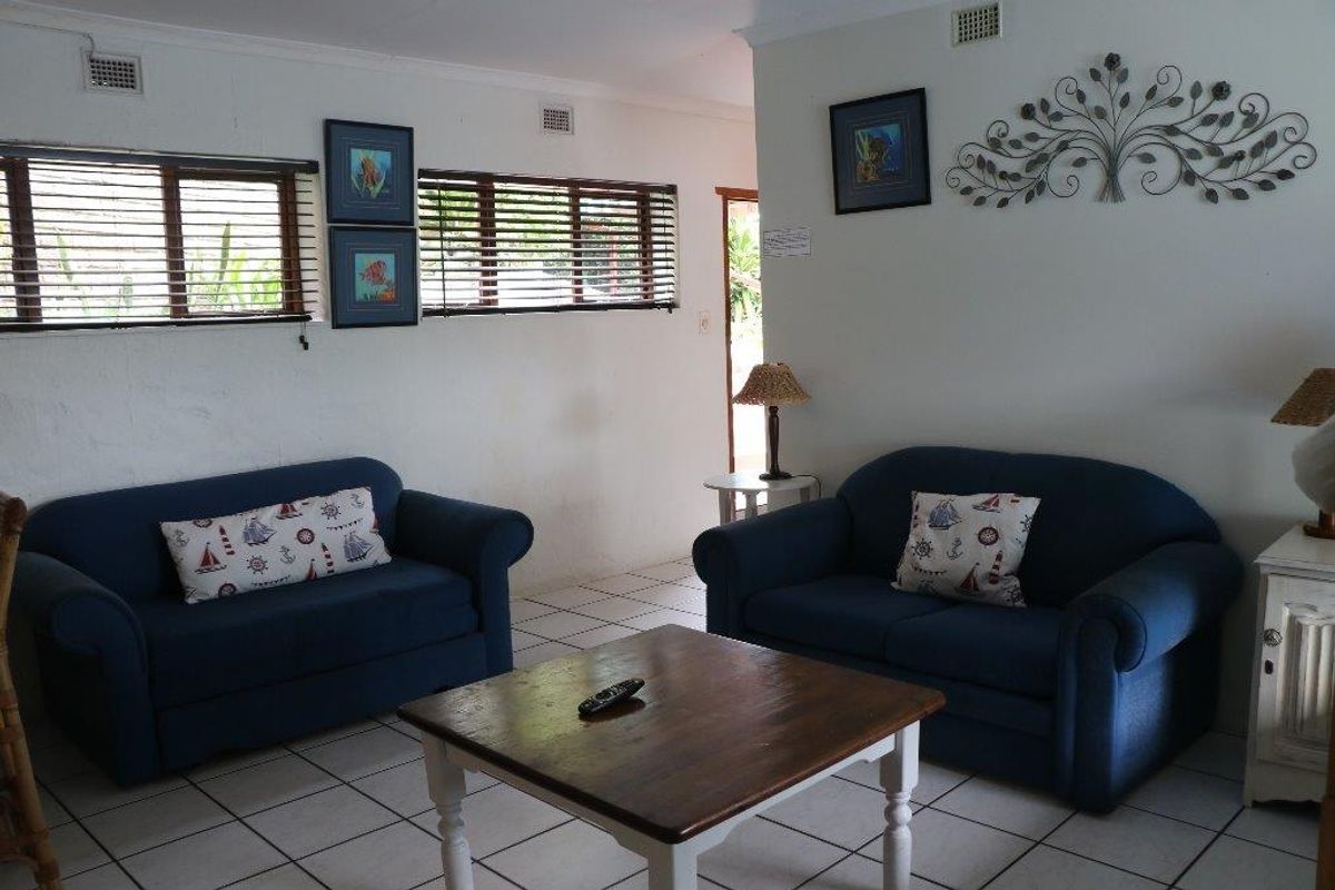 A living room area featuring tiled flooring, horizontal window blinds, and ceiling-mounted air vents.