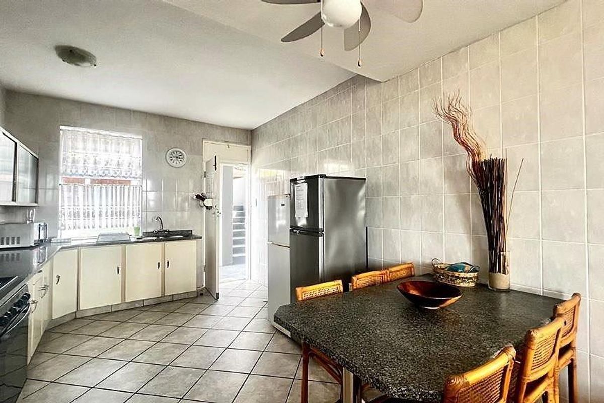 A functional kitchen featuring tiled walls and flooring, built-in cabinetry, and a dedicated dining area with a stone-topped table.
