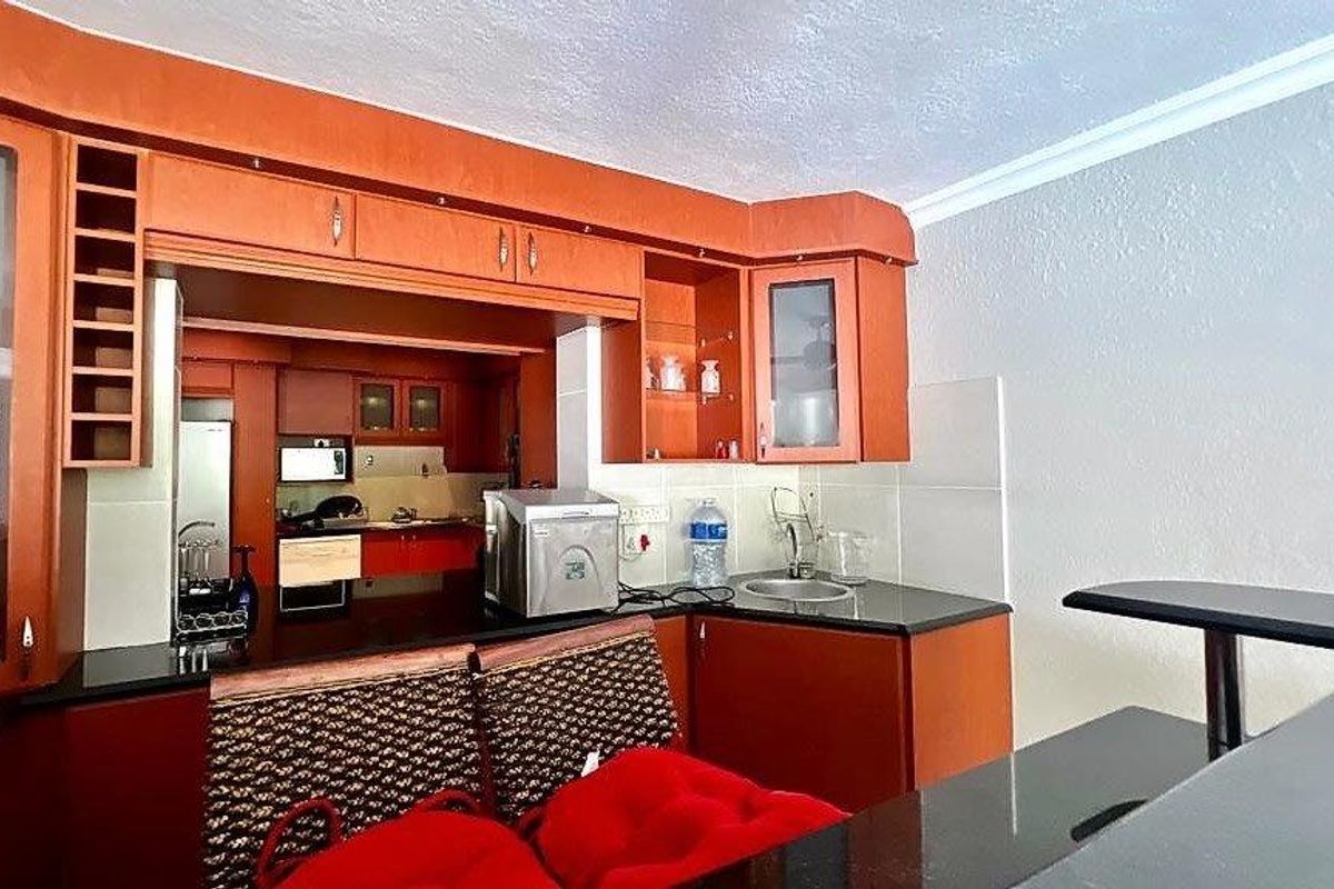 A functional kitchen featuring warm-toned wooden cabinetry, black granite countertops, and a convenient breakfast bar, offering a practical layout for daily meal preparation.