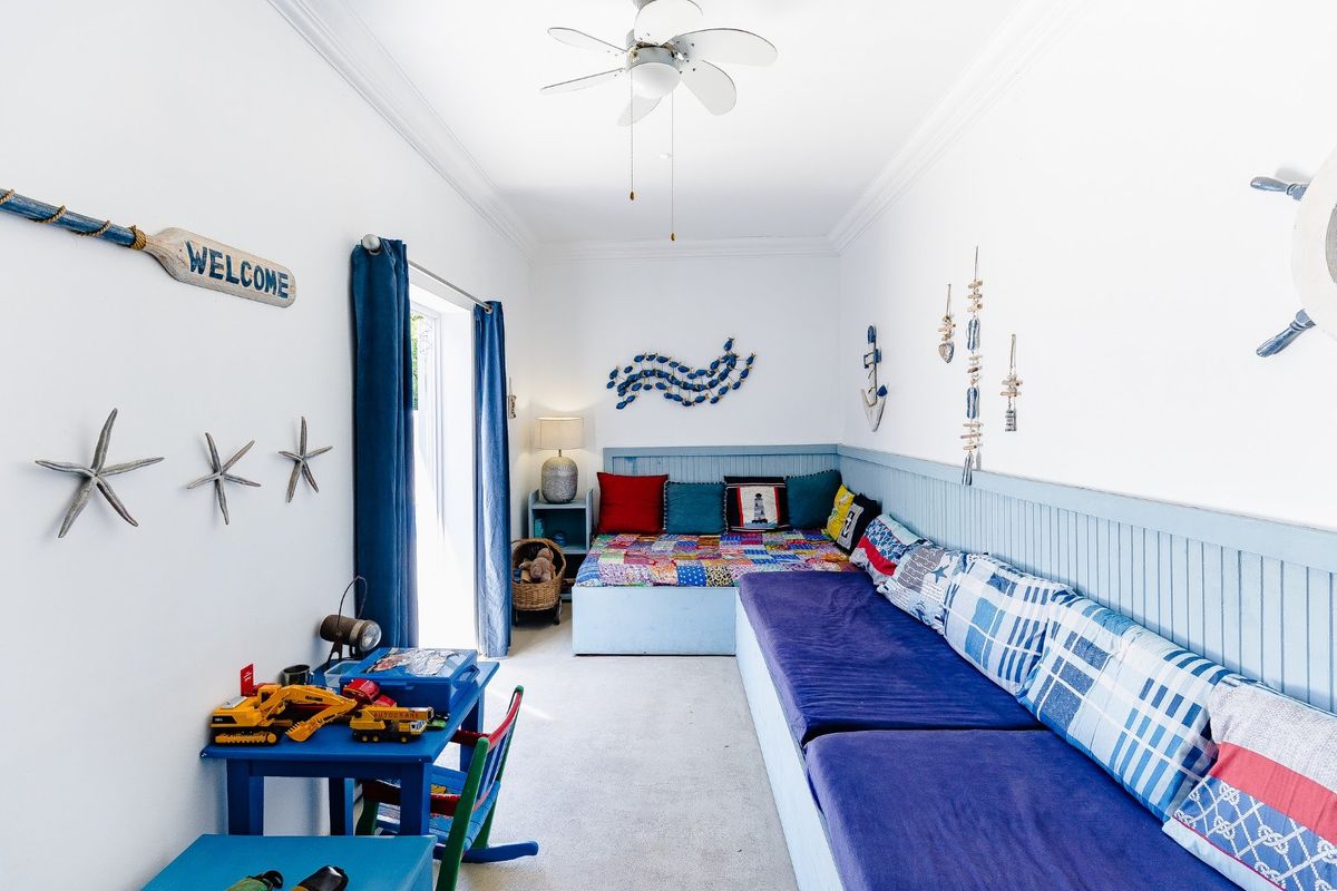 A bedroom featuring wainscoting, a ceiling fan, and a sliding glass door providing access to the exterior.