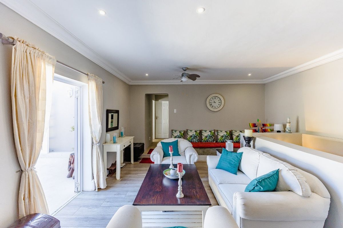 A bright and well-maintained living room featuring crown molding, recessed lighting, a ceiling fan, and direct access to an outdoor patio area.