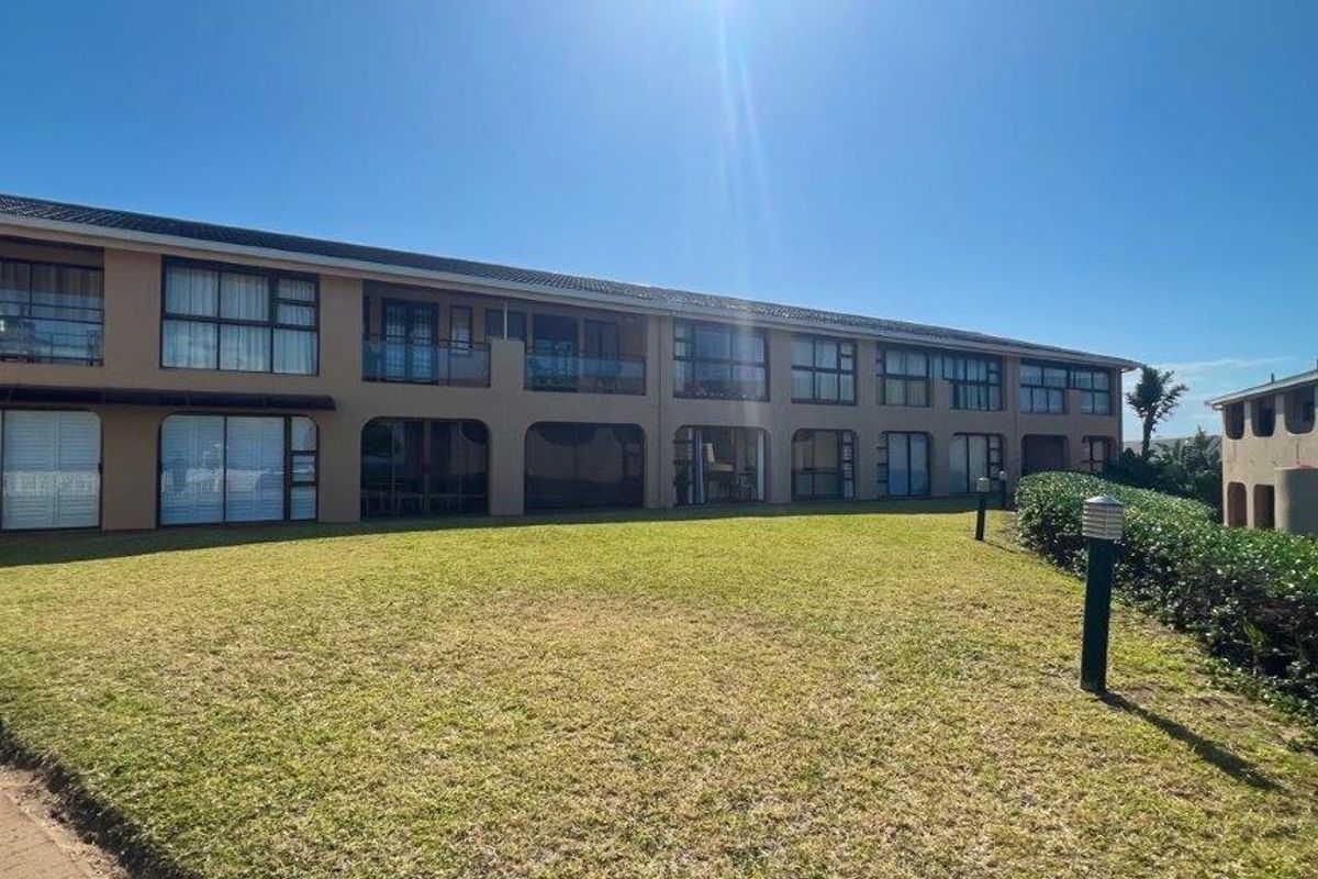 Rear view of a multi-story apartment complex featuring private balconies, sliding glass doors, and a well-maintained communal lawn area.