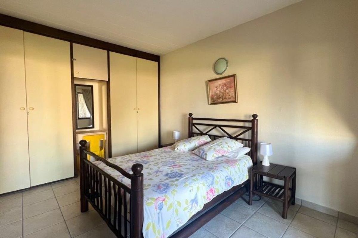A bedroom featuring built-in cupboards with a vanity section and tiled flooring.