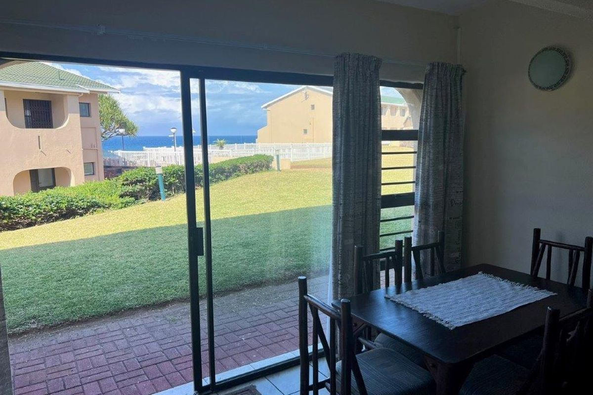 Living area featuring large sliding glass doors that open to a patio with garden and ocean views.