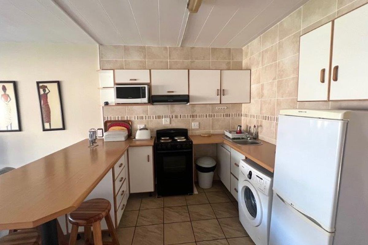 Functional kitchen featuring built-in cabinetry, laminate countertops, tiled backsplash, integrated oven with extractor fan, and a convenient breakfast bar for casual dining.