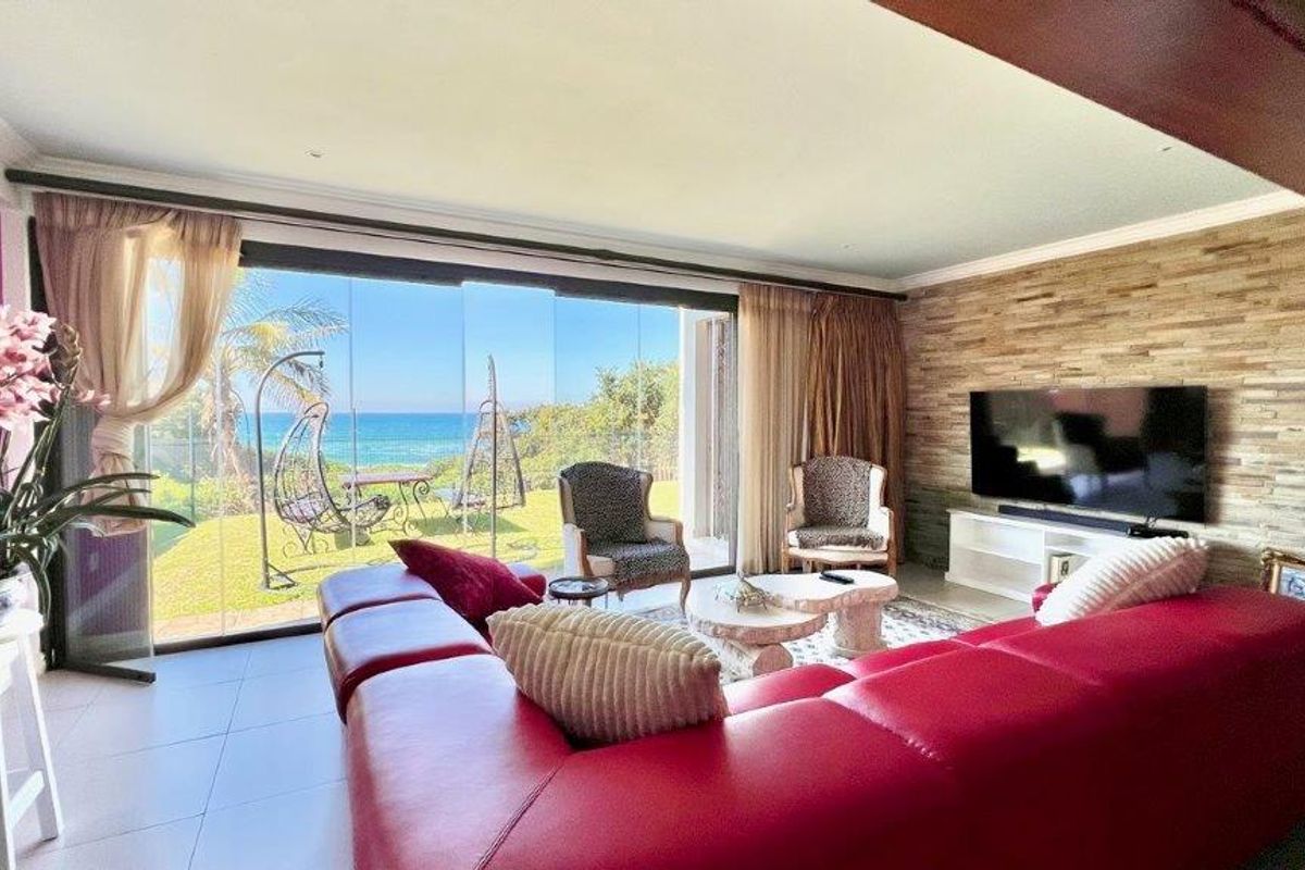 Spacious living area featuring large glass sliding doors that open to a scenic ocean view, complemented by a textured stone feature wall.