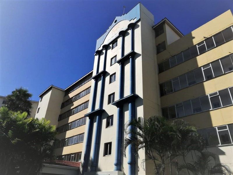 Exterior view of a multi-story apartment building featuring a prominent blue architectural facade detail and large windows.