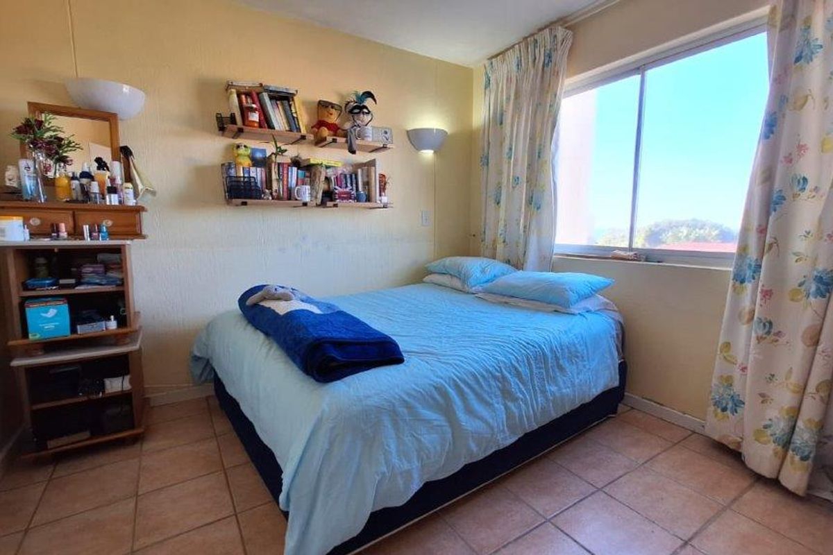 A bedroom featuring tiled flooring and a large window with natural light, providing a functional living space.