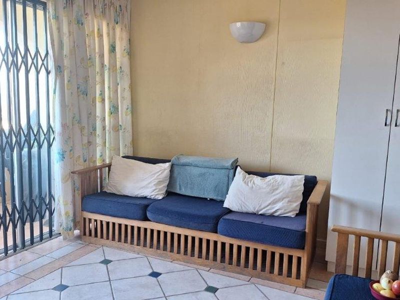 Living area featuring tiled flooring, built-in storage cupboard, and sliding door access to an outdoor balcony with security gate.