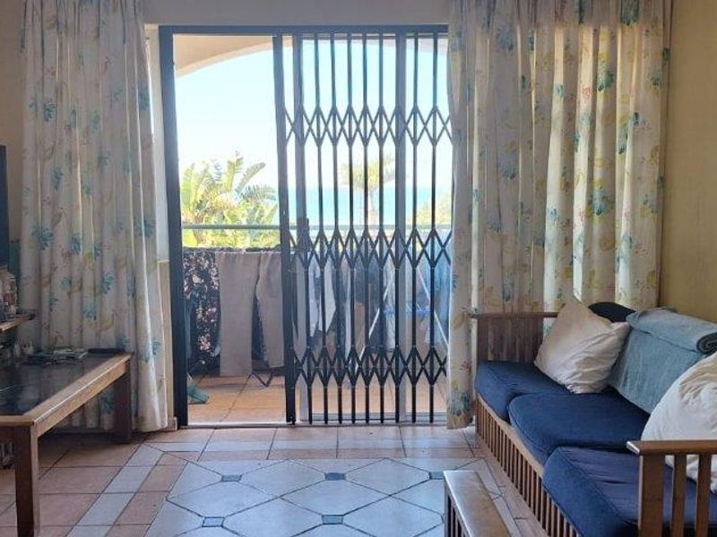 A living room featuring tiled flooring and a sliding door leading to a balcony with security gate.