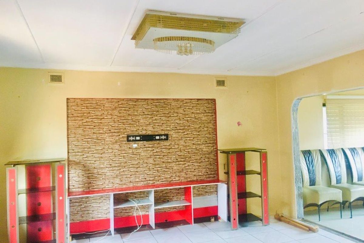 Living room featuring a stone-look feature wall with a built-in media console, tiled flooring, and an arched entryway leading to an adjacent space.