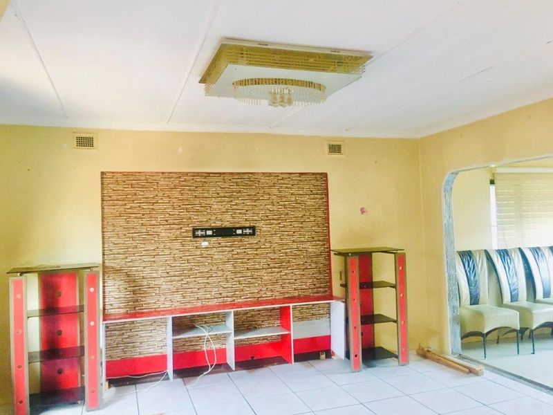 Living room featuring a stone-look feature wall with a built-in media console, tiled flooring, and an arched entryway leading to an adjacent space.