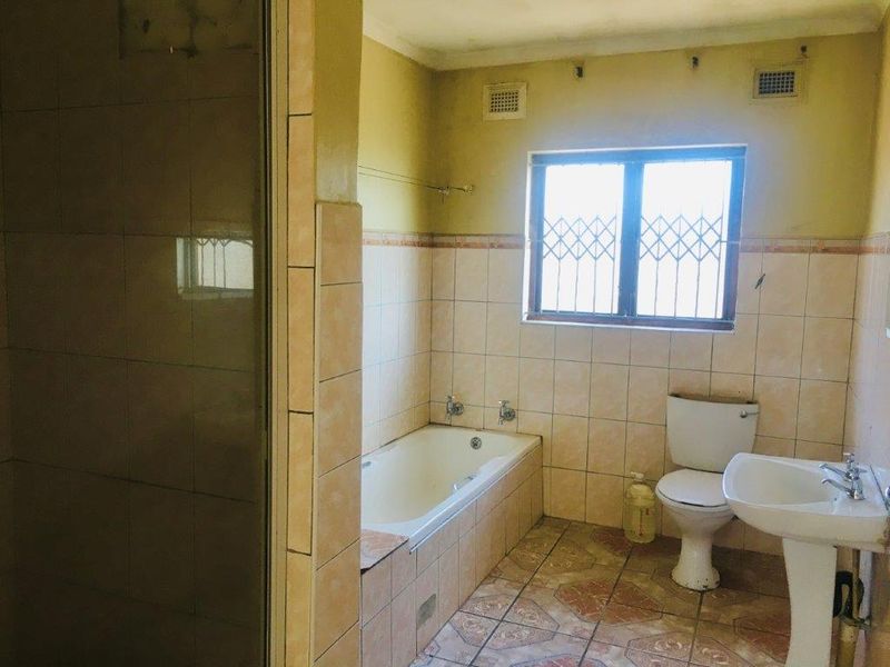 A dated bathroom featuring a built-in bathtub, pedestal sink, toilet, and separate shower enclosure with original tile finishes.