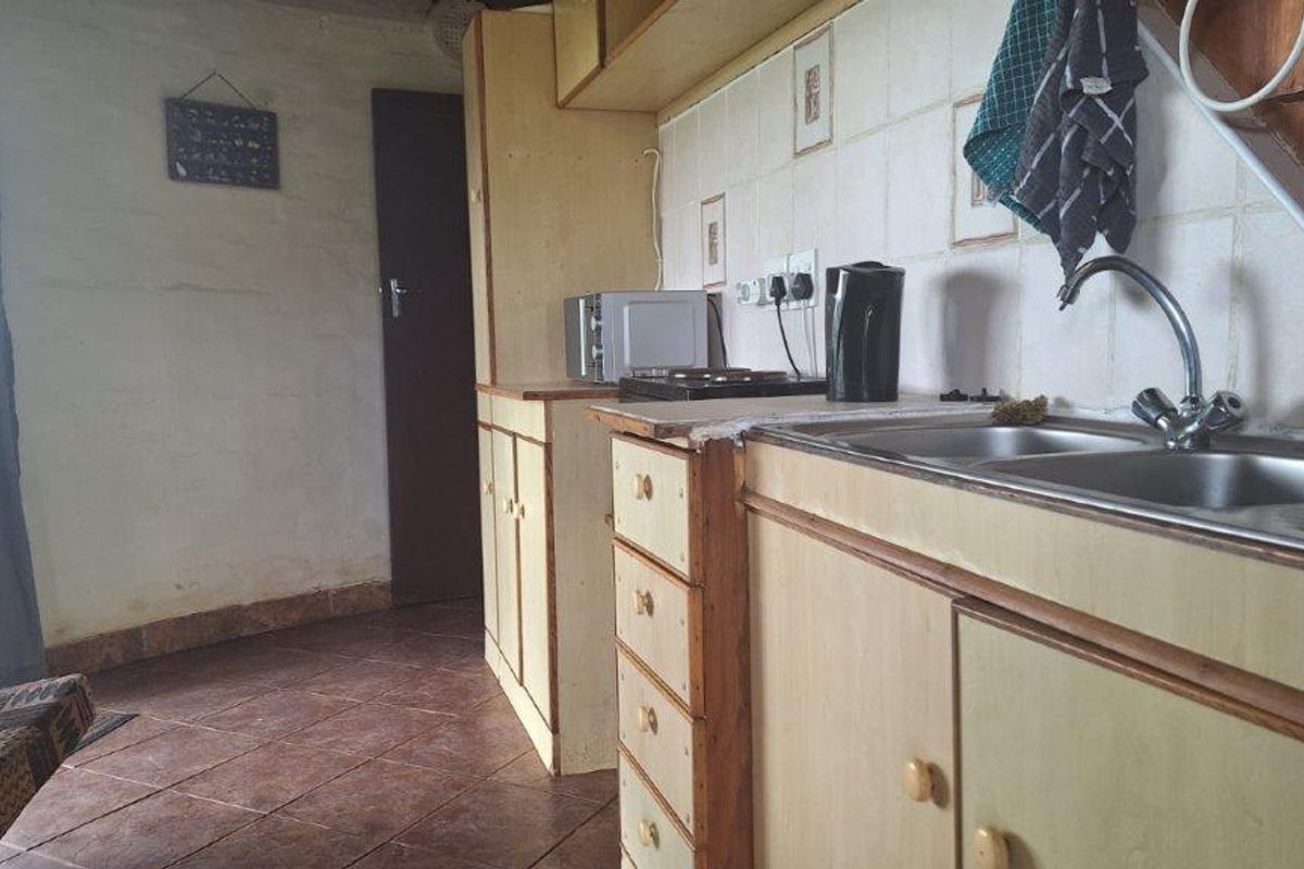 A dated kitchen area featuring original cabinetry, a double basin sink, and tiled splashbacks, offering potential for modernization and renovation.