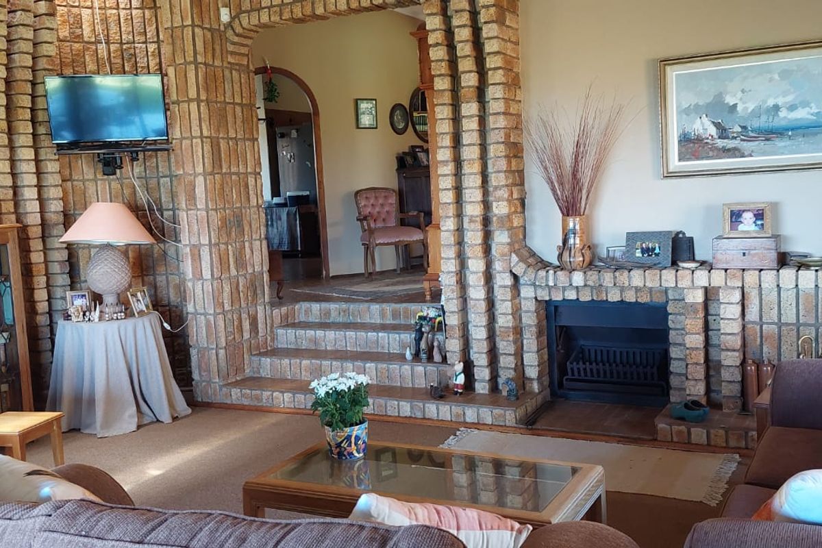 Spacious living room featuring a prominent brick fireplace and distinctive brick archway leading to an adjacent room, showcasing traditional architectural character.