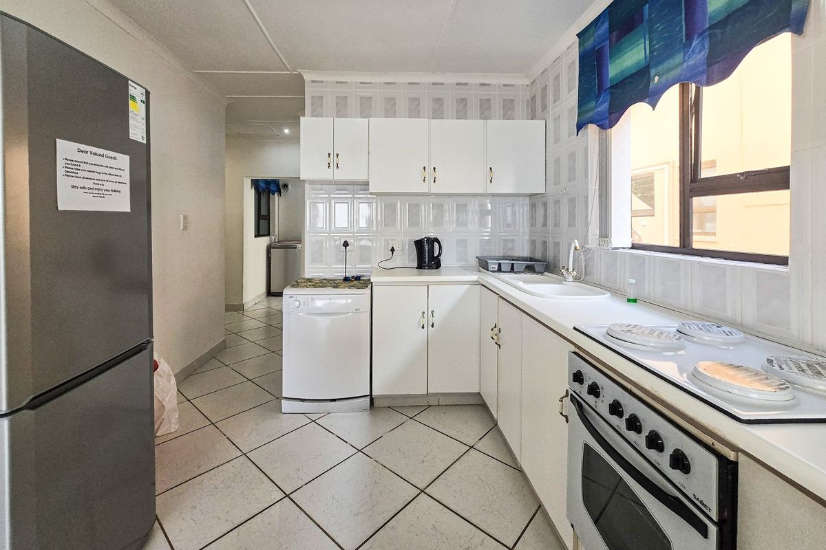 A functional kitchen featuring white cabinetry, tiled splashbacks, a built-in oven with hob, and tiled flooring, offering a practical layout for daily meal preparation.