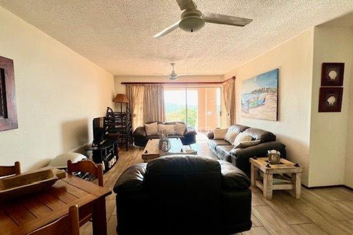 Spacious living area featuring tiled flooring, ceiling fans, and large sliding glass doors that provide access to the outdoor space.