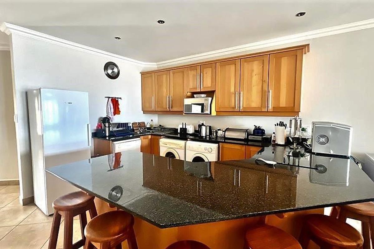 Functional kitchen featuring wooden cabinetry, granite countertops, a breakfast bar, and integrated appliances, offering a practical layout for daily use.