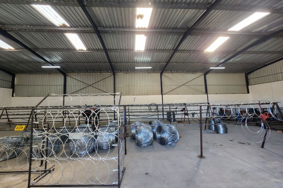 A spacious industrial warehouse unit featuring high ceilings with exposed steel trusses, corrugated metal roofing, and durable concrete flooring.