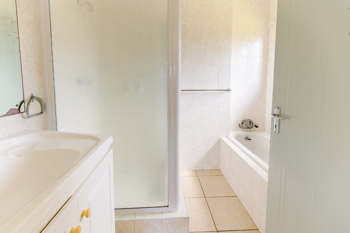 A functional bathroom featuring a built-in vanity, a separate shower enclosure, and a tiled bathtub area with neutral finishes.