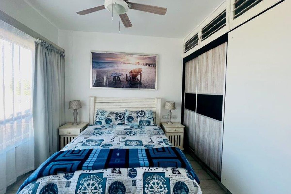 A well-maintained bedroom featuring a ceiling fan and extensive built-in sliding door wardrobes, providing ample storage space.
