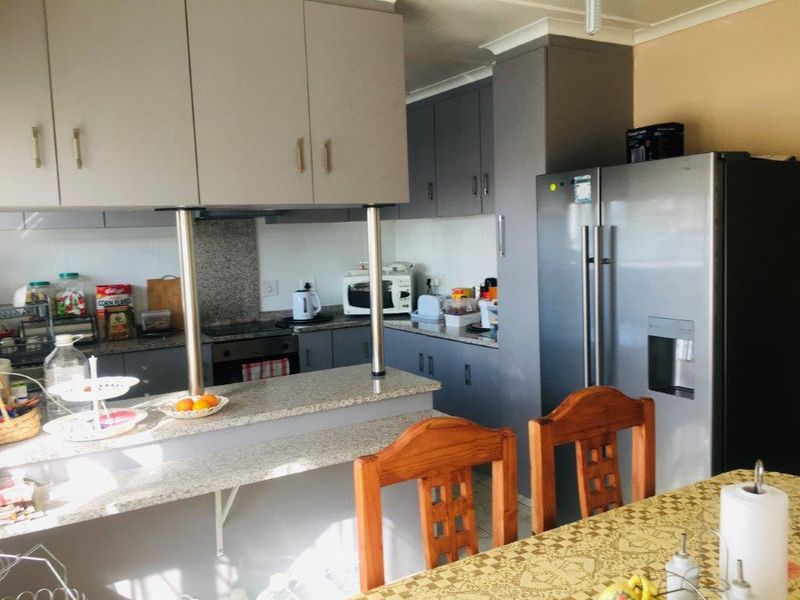 A functional kitchen featuring granite countertops, ample built-in cabinetry, a breakfast bar, and integrated appliances, offering a practical layout for daily cooking.