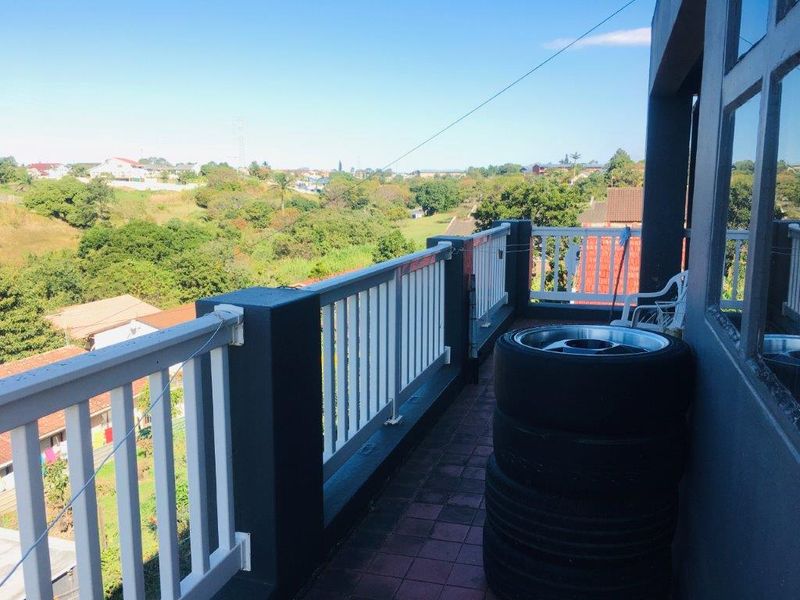 An elevated balcony featuring a balustrade and tiled flooring, offering expansive views of the surrounding neighbourhood and landscape.